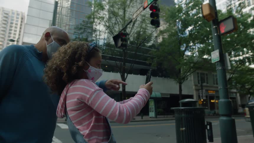 A father and daughter taking pictures in a big city