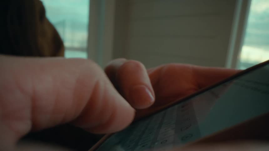 Both hands are holding a smart phone as a person is texting with their thumbs