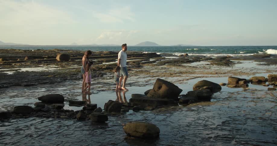 Parents and daughters wander on muddy beach near the sea