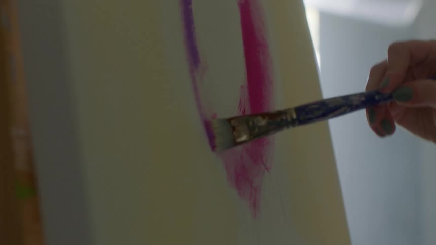 A painter draws a purple line on a canvas