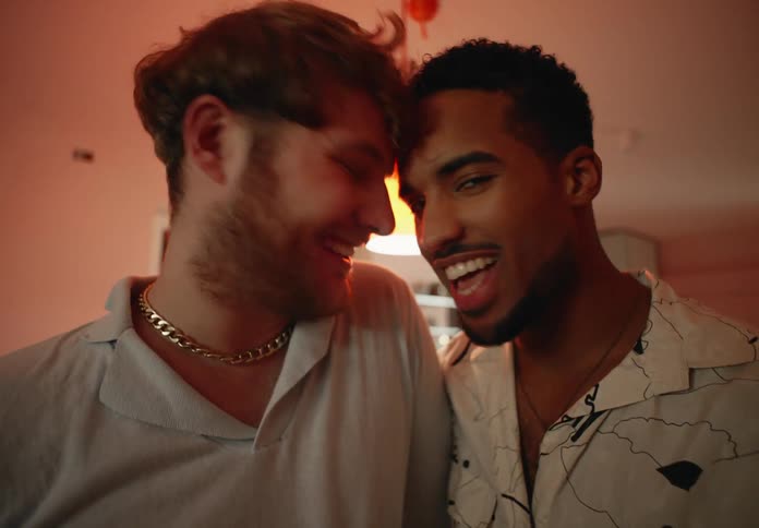 Two men holding each other close as they smile laugh and nuzzle each others noses