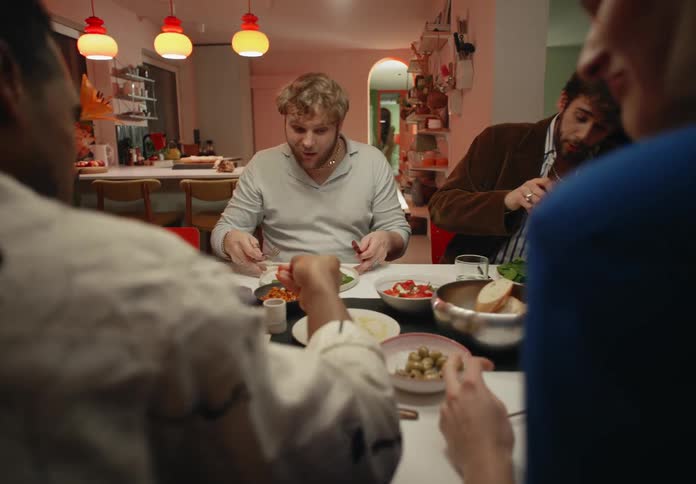 A group of four people sit around the table eating dinner and laughing