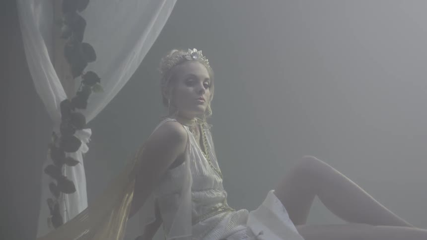 Woman in a toga lounges on a bed
