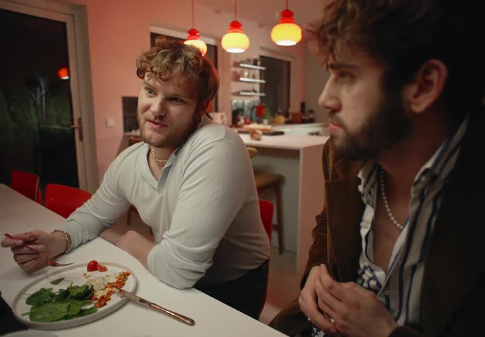 Friends sit at dinner table near kitchen at night talking