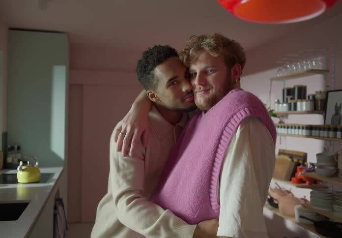 Male couple smiles while cuddling in kitchen