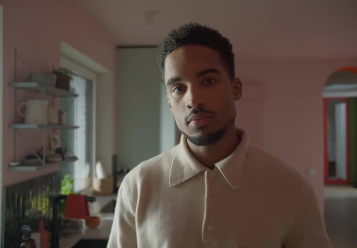 A man is standing inside a room as he turns his head and looks forward