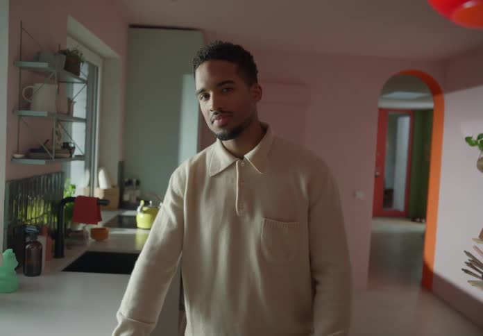 A man is standing in a room as he looks ahead and smiles