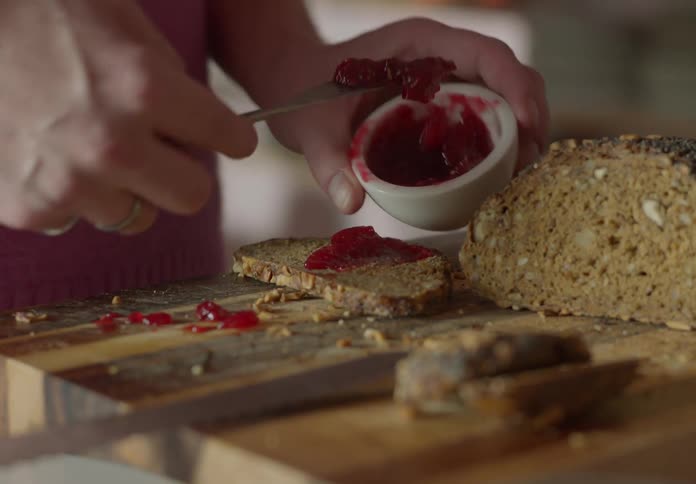 Person spreading jam on bread