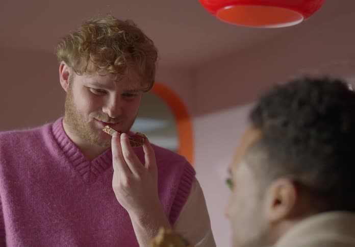 Two men eat toast in a restaurant while talking happily
