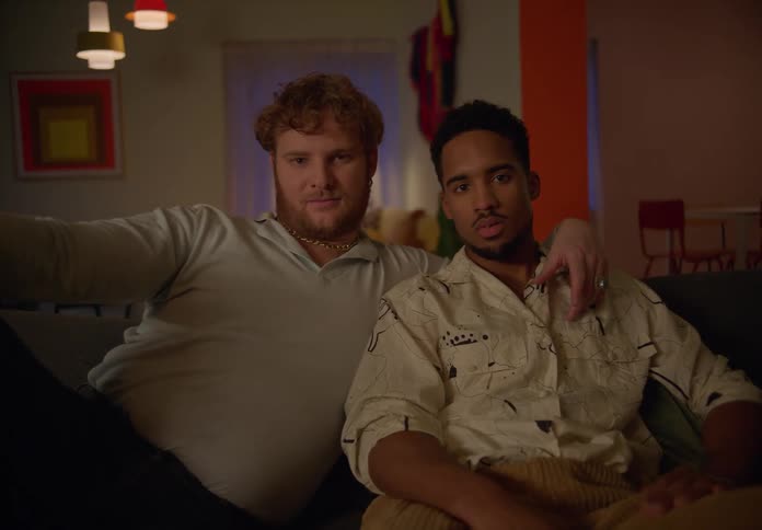 Gay couple sits on couch looking into each others eyes in the living room