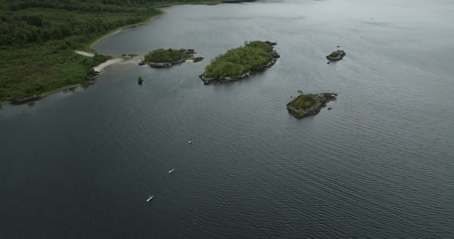 A large lake with little islands scattered throughout and three standup paddleboarders