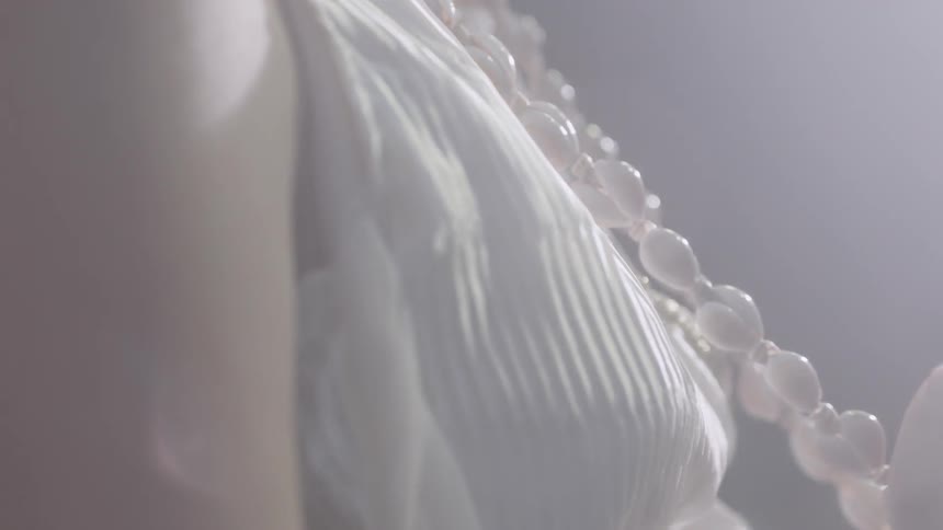 A woman adjusts her shell necklace