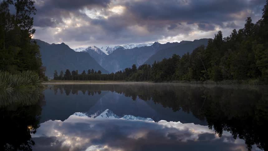 Landscape of clouds floating over serene lake forest and mountain range