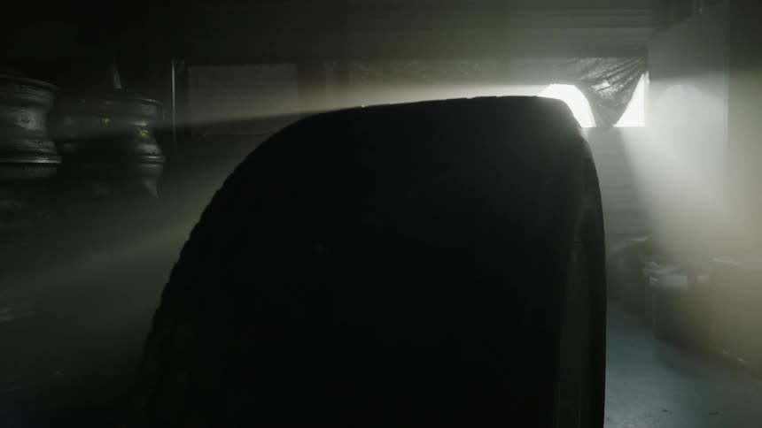 Sunlight streaming into a garage as a wheel rolls across the floor