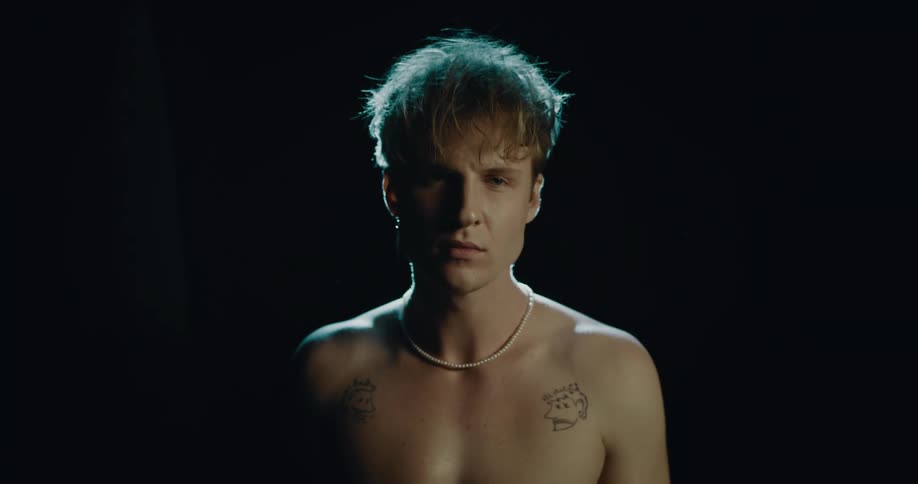 A man taking off his shirt and smiling into the camera