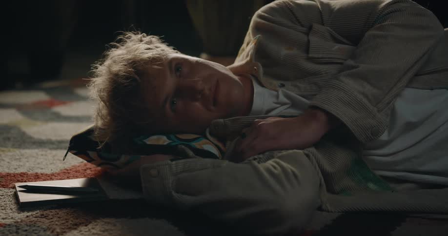 A man rests his head on a small pillow on the floor