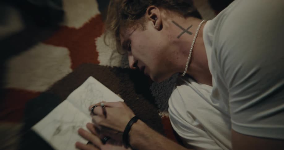 Distraught man lying on floor scribbles in notebook