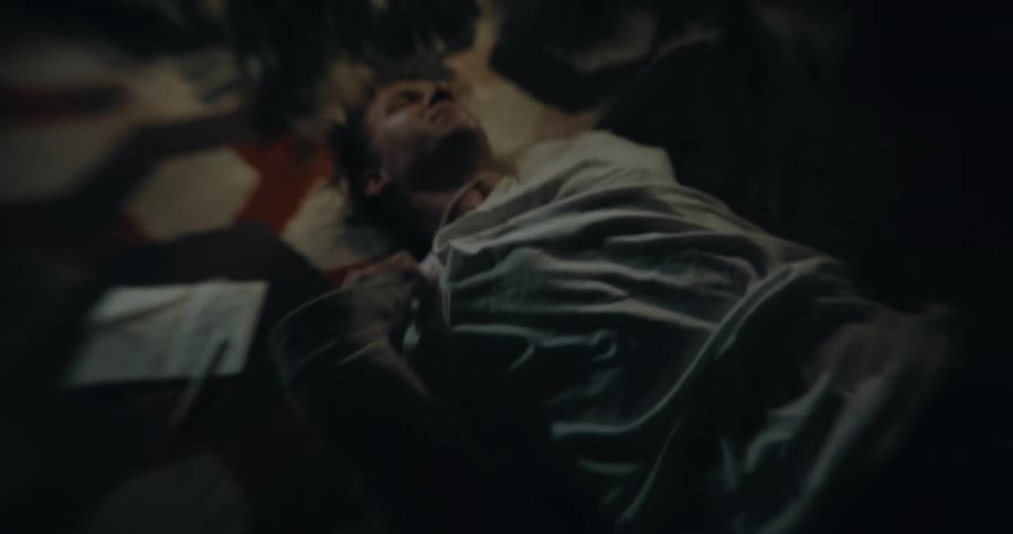 A man tries to rip off his shirt while lying on a rug