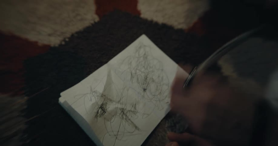 Man lying on rug scribbles in notebook while crying