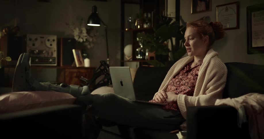 A woman waves to her laptop camera during a video call at home