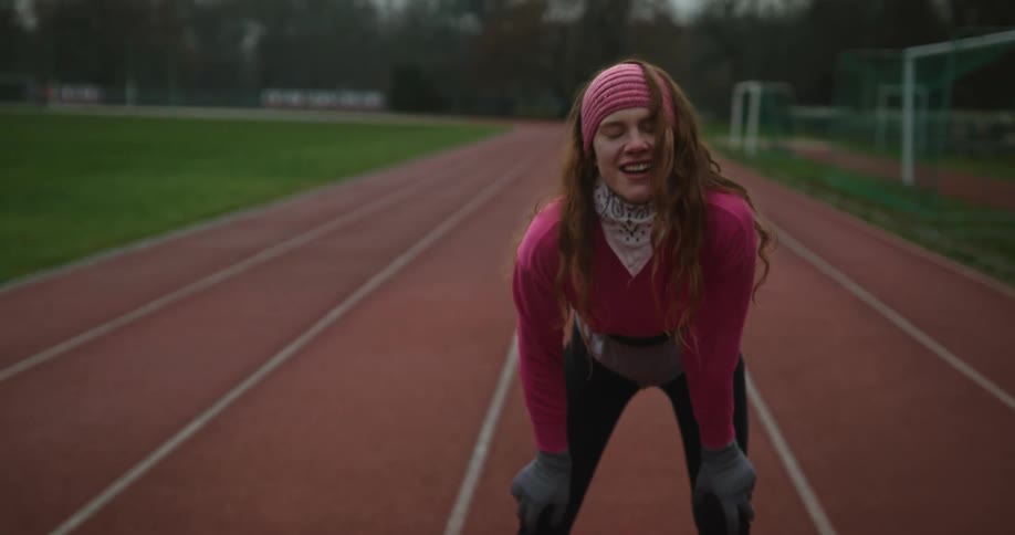 A woman running on an outdoor track on a chilly day