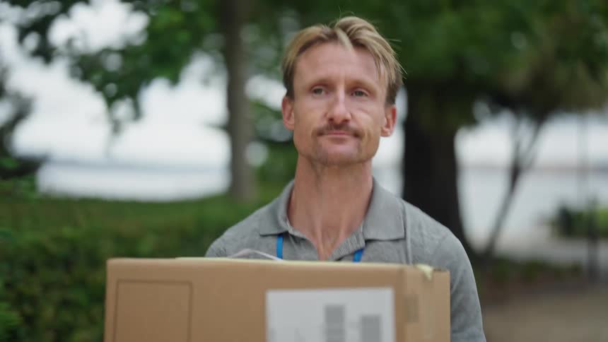 A man is walking while holding a package