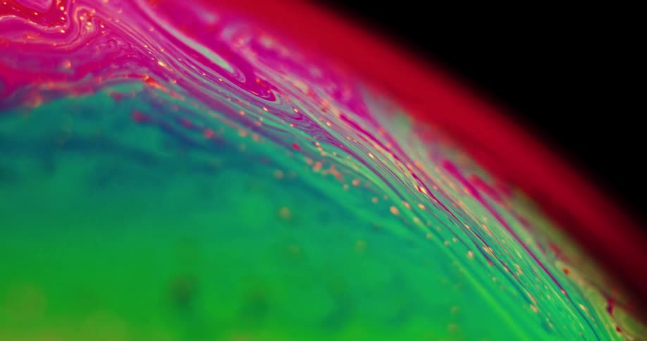 The organic colored surface of a sphere mixes and blends as it turns and red and green form magenta and purple with yellow dots