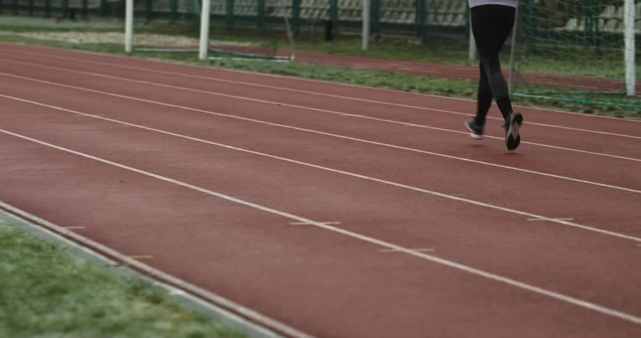 A woman is shown jogging in an outdoor setting wearing athletic clothing and running shoes