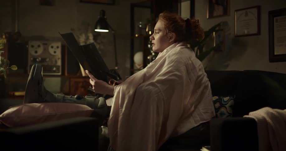 A woman looks at some papers while using a laptop