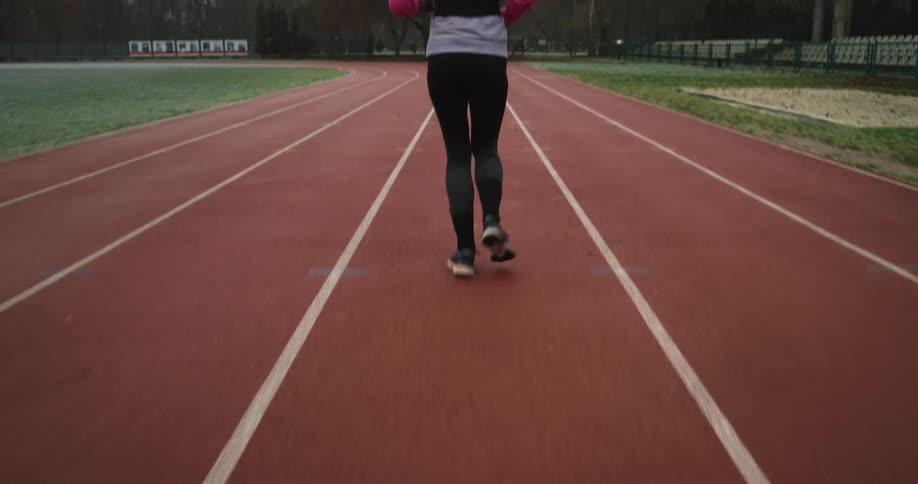 A female is jogging on a track during the spring