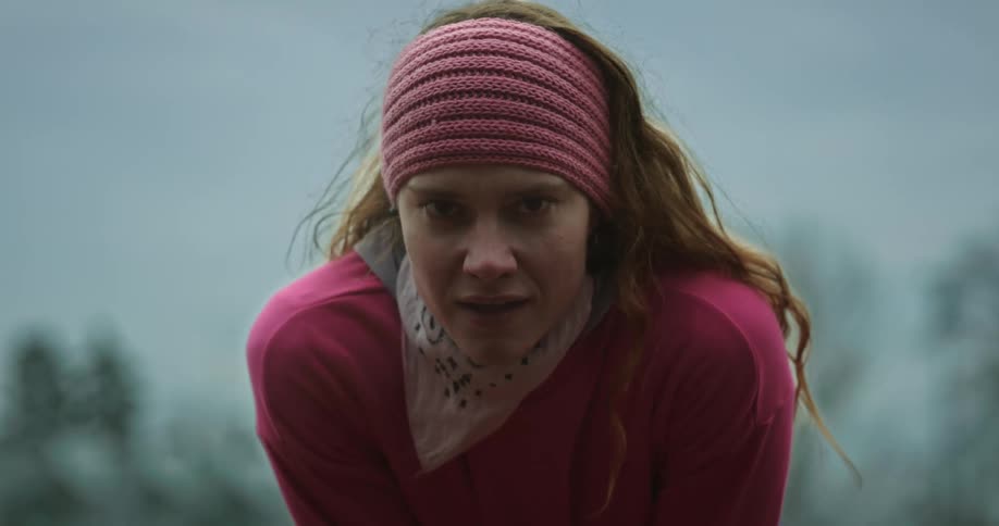 Woman leans over catching her breath and letting it fog up the air