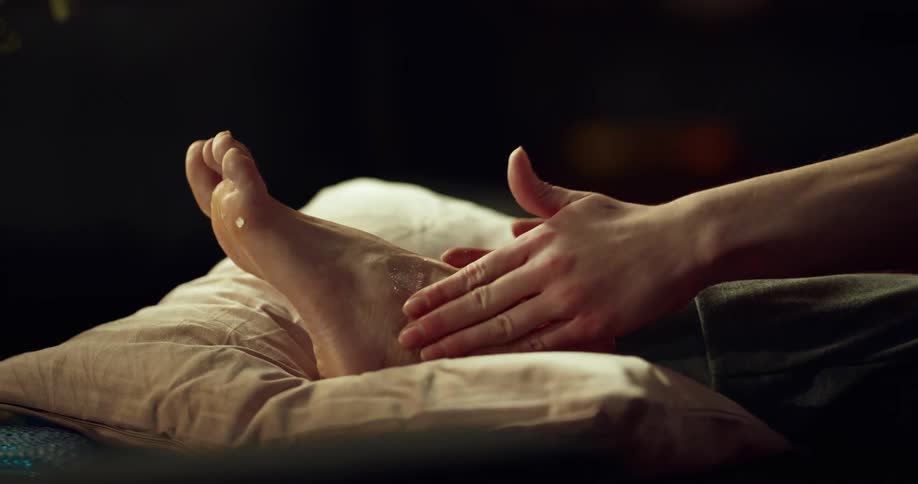 Woman massaging ointment on injured foot