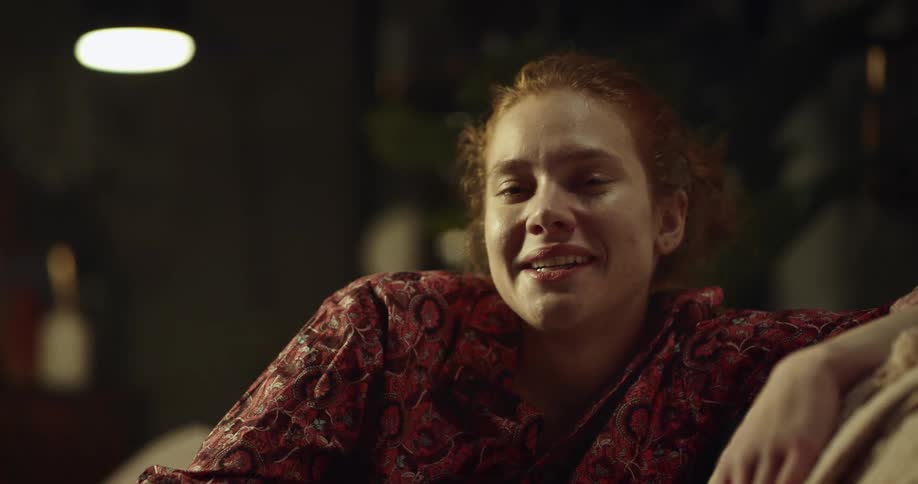 A woman sits and laughs and puts her head in to her arm