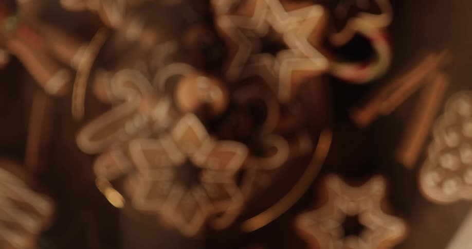 Various shapes of gingerbread cookies sit on a plate with a flickering light casting onto them from off camera