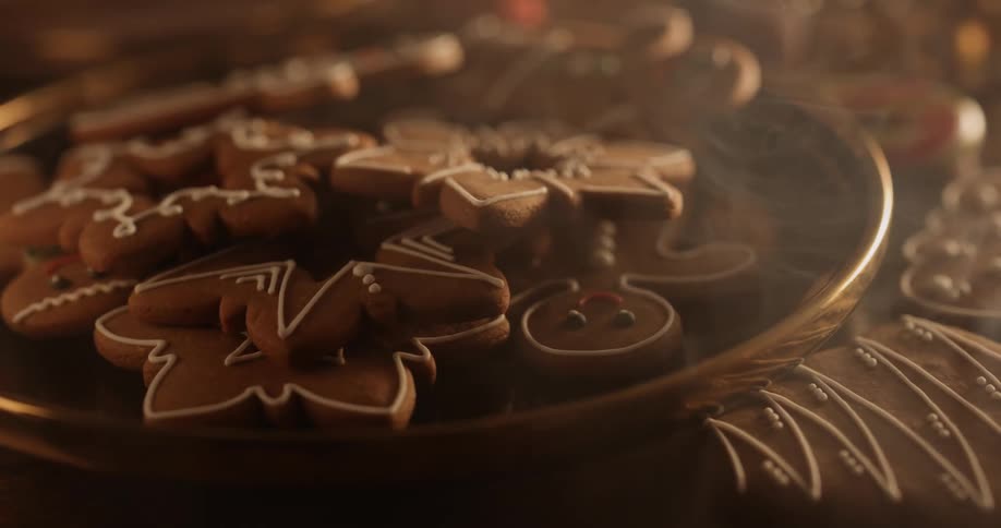 Holiday gingerbread cookies decorated with icing are on a table with a candy cane as smoke floats over the table