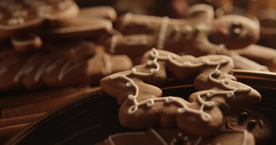 Holiday cookies are on a plate and on the table as a gingerbread man looks up smiling