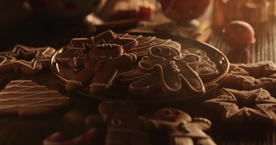 Holiday cookies are on a plate and on the table as gingerbread men look up smiling