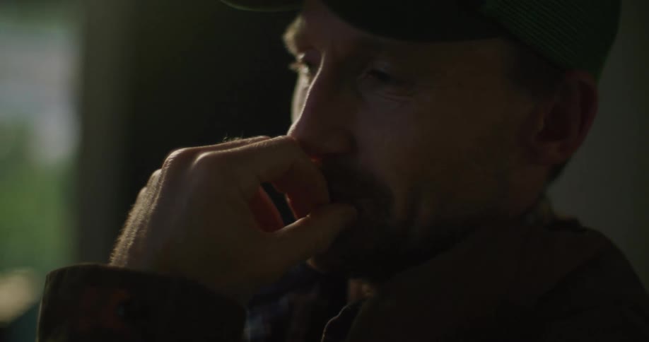 Bearded man trembles and puts his hand to his mouth while he talks