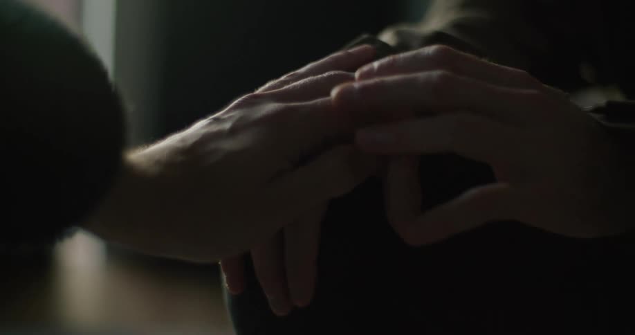 Woman touches mans shaky hands in room
