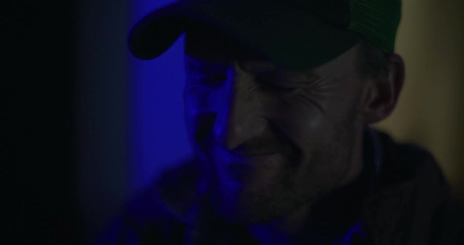 Man looking upset while police lights flash off screen