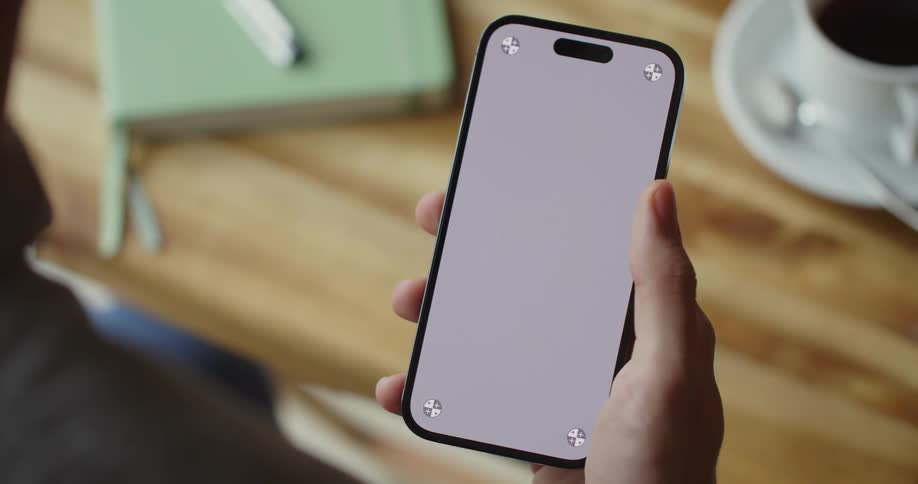 A person is looking at their phone and sitting at a table