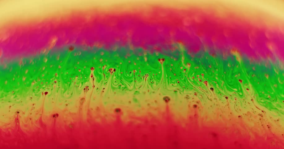 Fluorescent stripes of green blended with yellow moves up into red creating purple and orbs of color move up