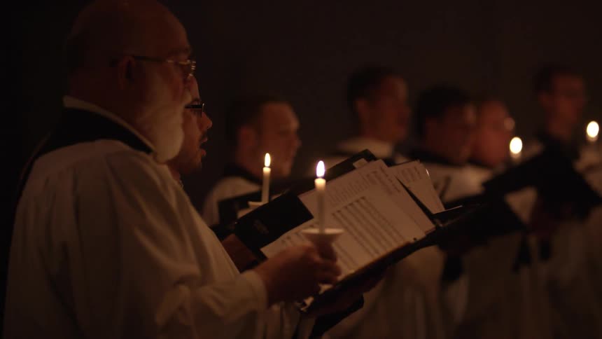 People are holding candles and singing in church