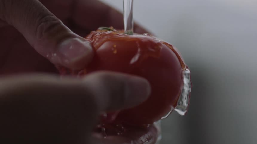A person washes a tomato
