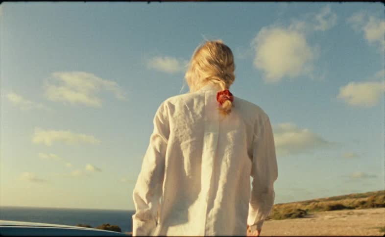 A woman runs to the cliff from her car
