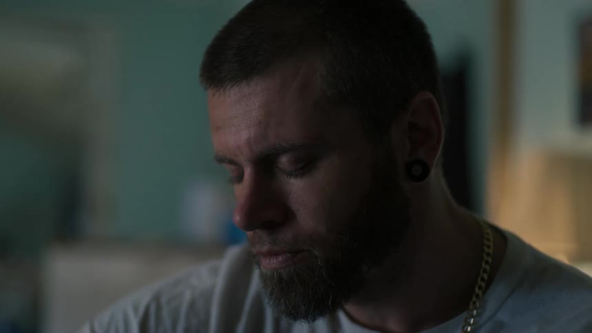 Bearded man closes his eyes and lowers his head a bit