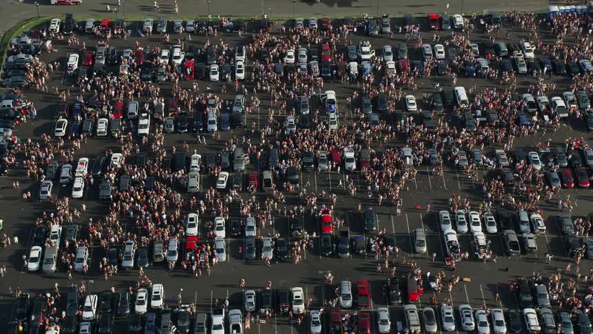 Aerial footage of crowds tailgating in Campbells Field parking lot Camden NJ during summer
