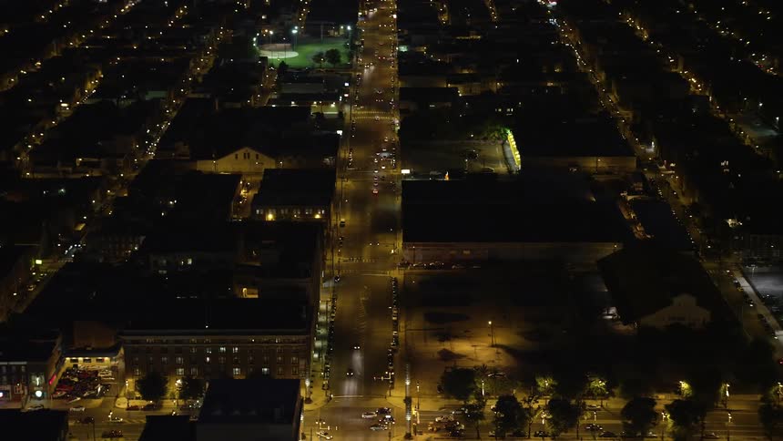 A nighttime aerial shot of busy city streets and a dark industrial warehouse building in South Philadelphia Pennsylvania