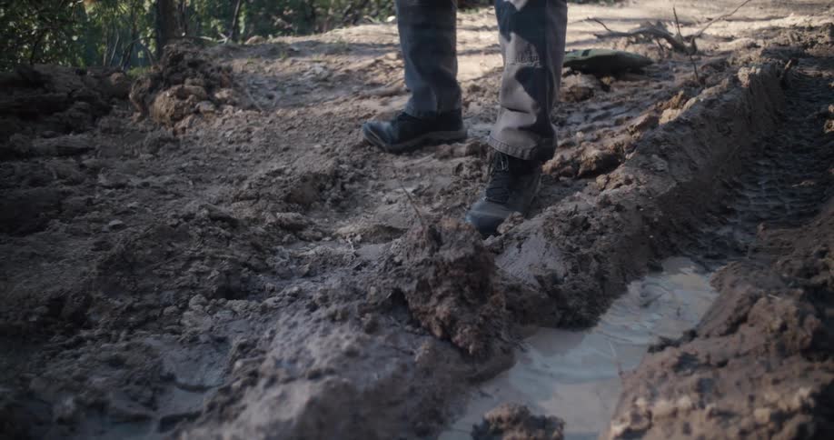 Man digs near puddle in bare ground