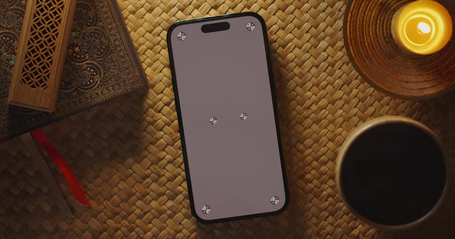 A person sets a cell phone down next to a mug and a candle